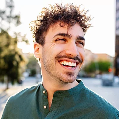 A man with a green shirt smiles.