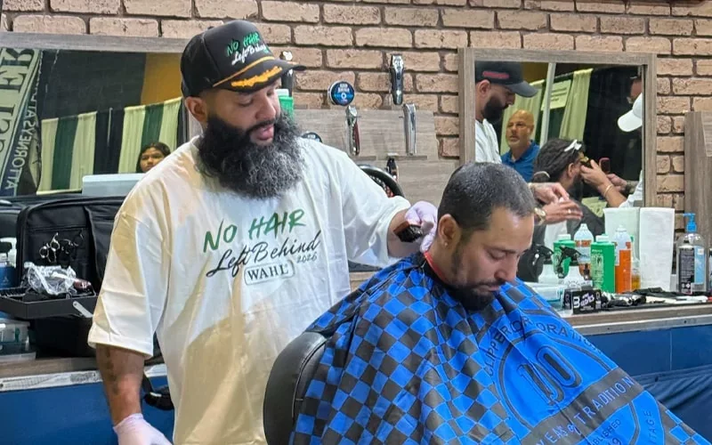 Barber cutting a man’s hair in a barbershop.