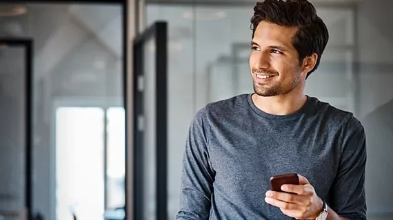 A man holding his phone while standing in a bathroom.