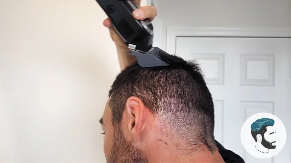 A close up of a man using a Wahl clipper to cut the top of his head.