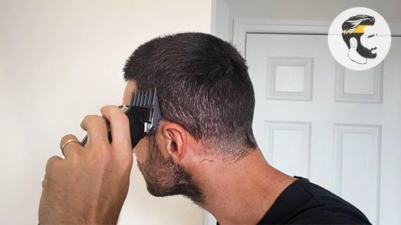 A man using a Wahl hair clipper to cut the side of his head.