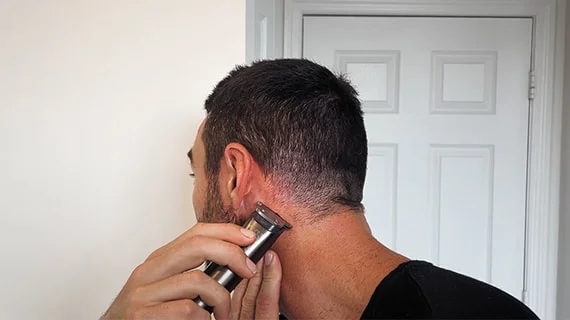 A man using the inverted clipper technique to touch up his haircut.
