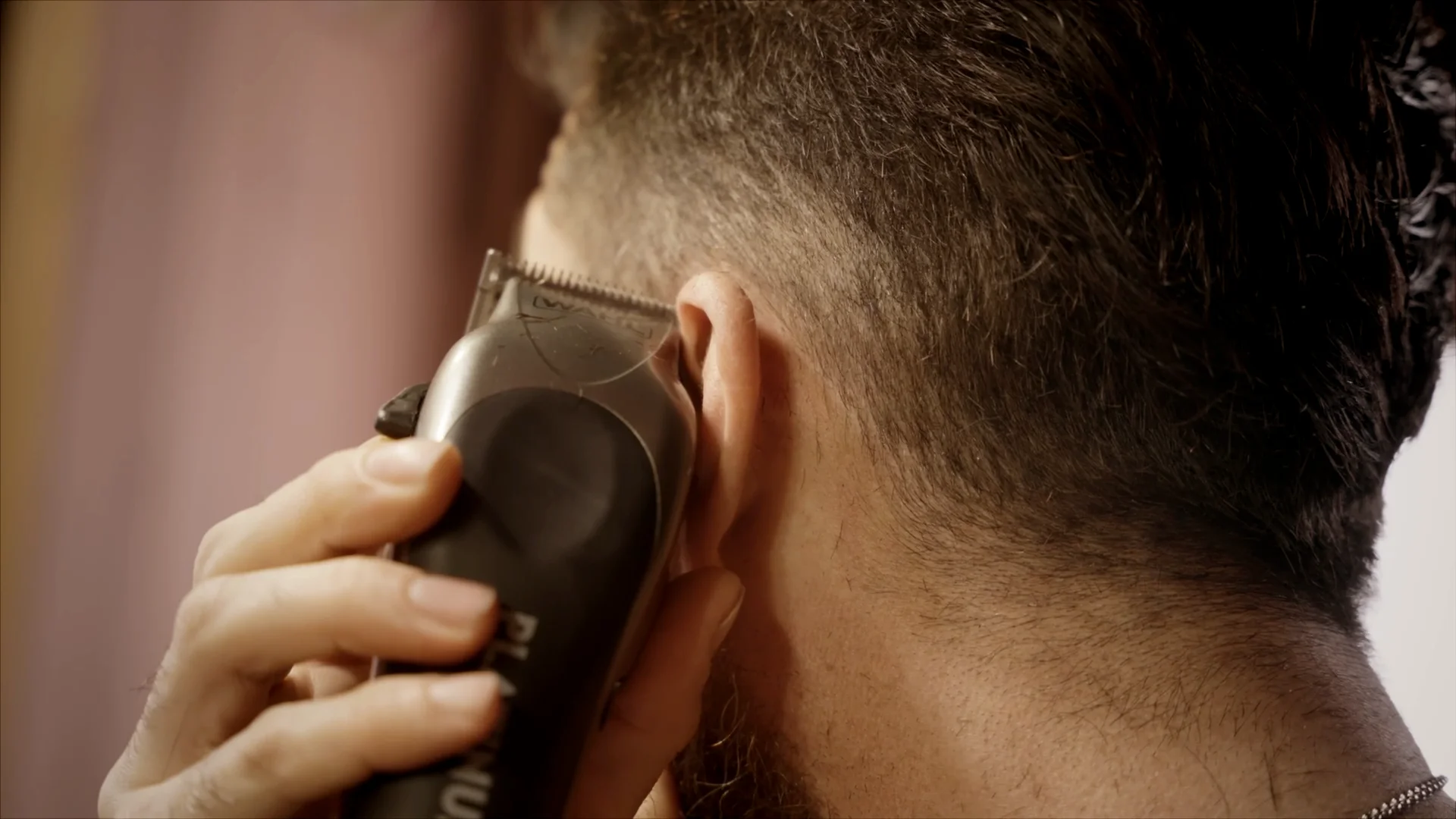 A man using a Wahl trimmer to trim around his ears.