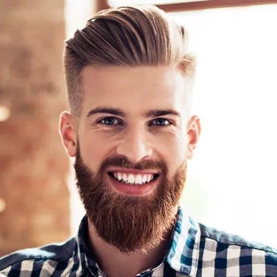 A smiling, bearded man with a undercut hair style. 