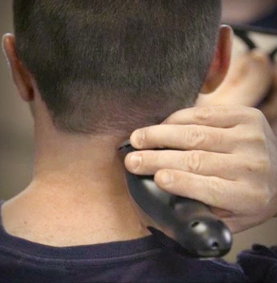 A man touching up his neck hair after giving himself a haircut.