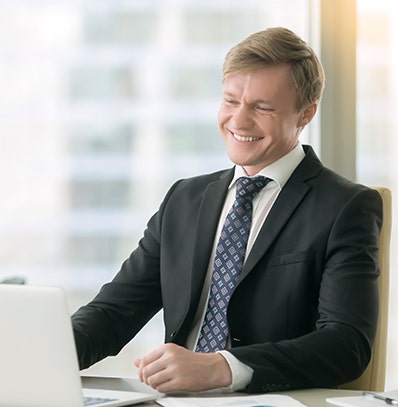 A man dressed in a business suit working on his laptop. 