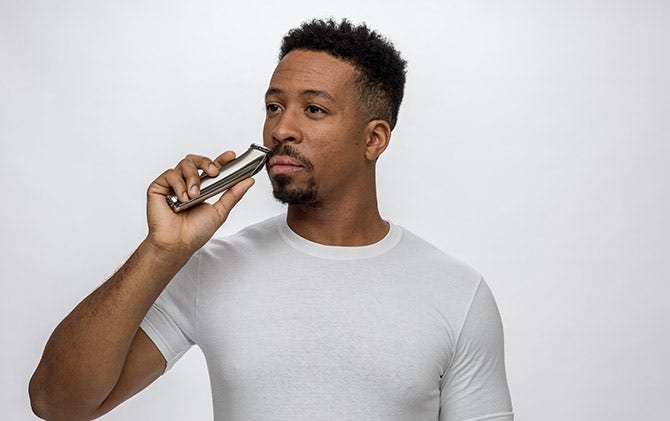 A man trimming his mustache with a Wahl trimmer. 