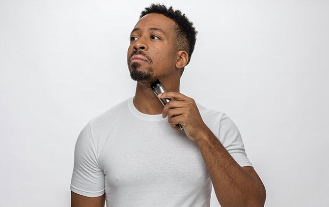 A man trimming and cleaning up his neck hair with a Wahl trimmer. 