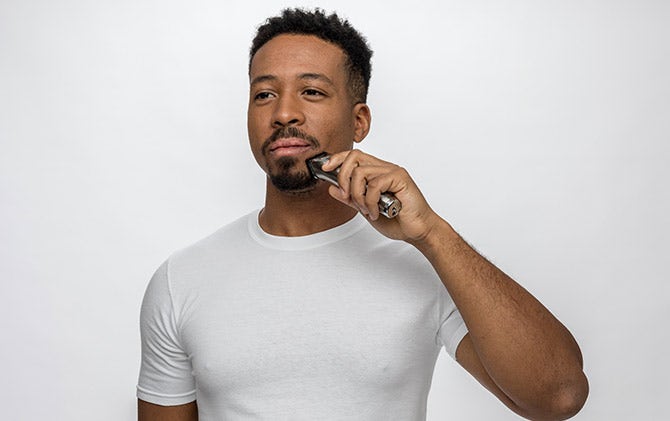 A man maintaining his goatee style with a Wahl trimmer. 