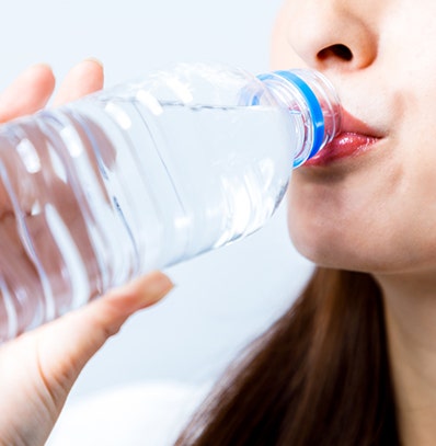 A woman drinking water from a bottle. 