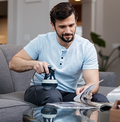 A man using a handheld Wahl massager to massage quad or upper thigh.