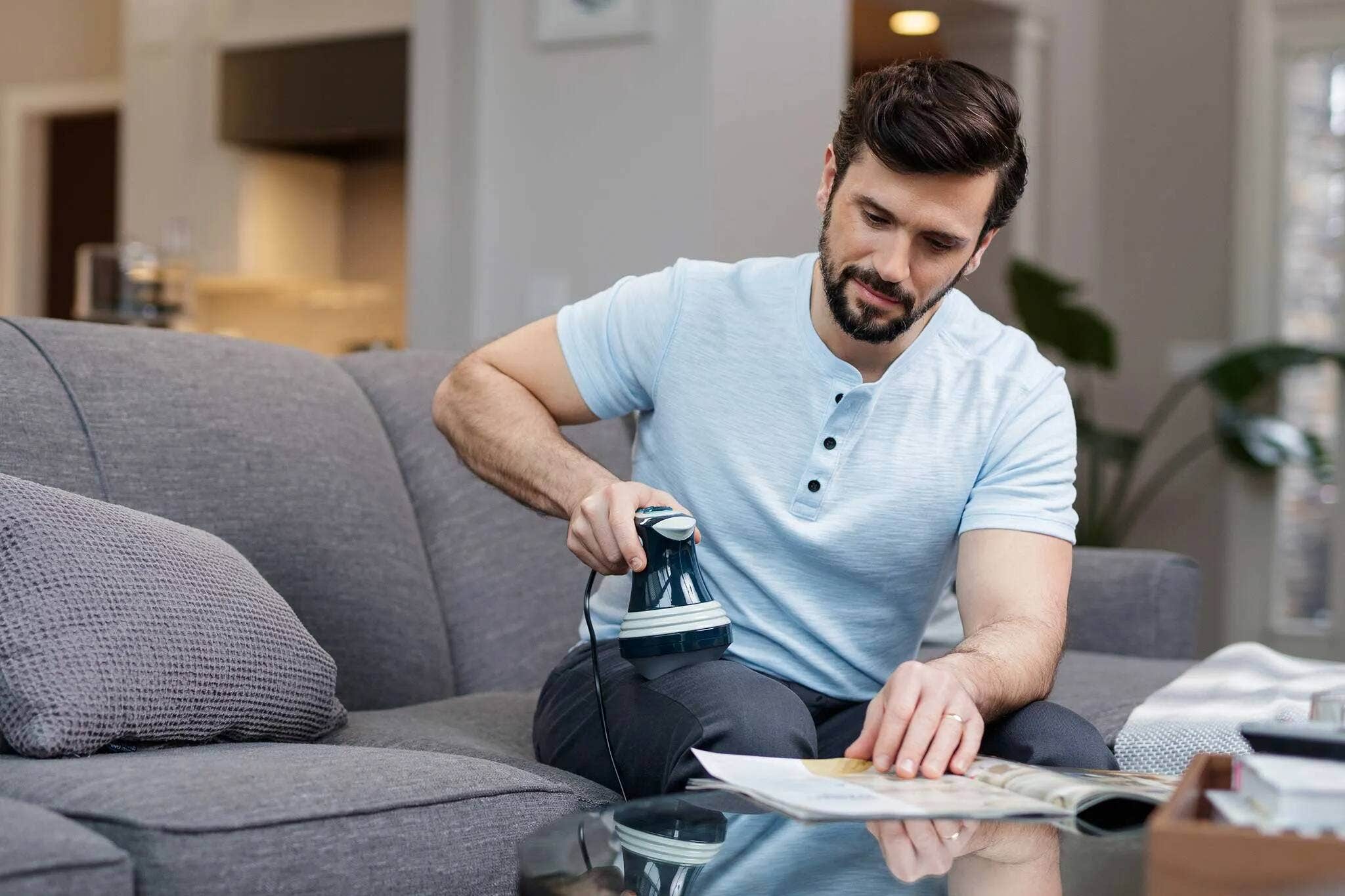 A man using a Wahl handheld massager on his quad or upper thigh.