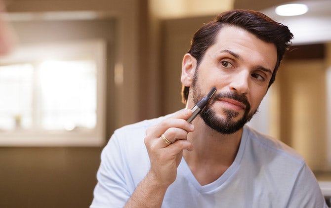 A man shaping his mustache with a Wahl trimmer and attachment head. 