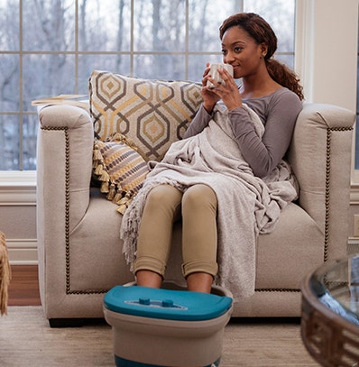 A woman relaxing while using a foot massager. 