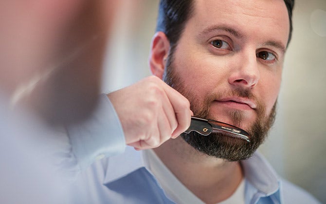 A man combing his full beard.