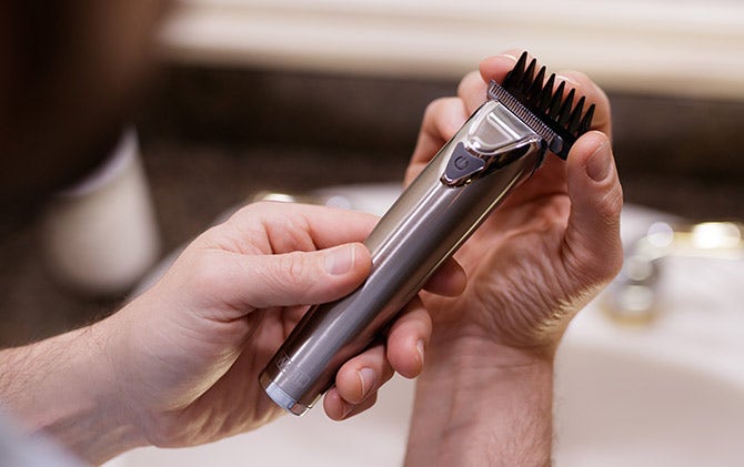 Someone attaching a guide comb head attachment to their Wahl trimmer. 