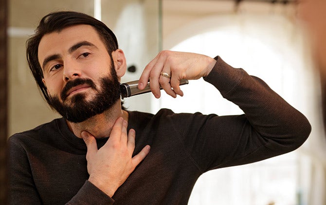 A man cleaning up his beard line with a Wahl trimmer.