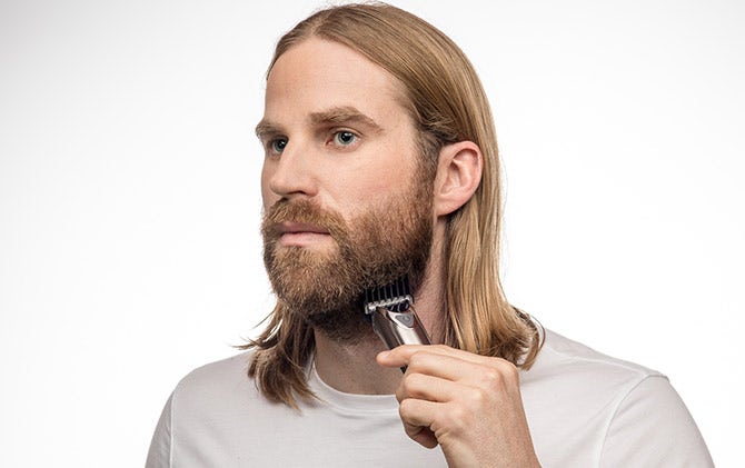 A man trimming his full beard with a Wahl trimmer.