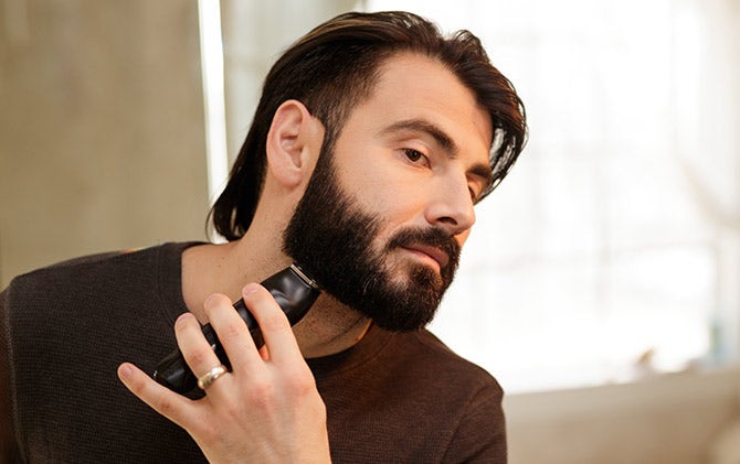 A man shaping his beard with a Wahl trimmer. 