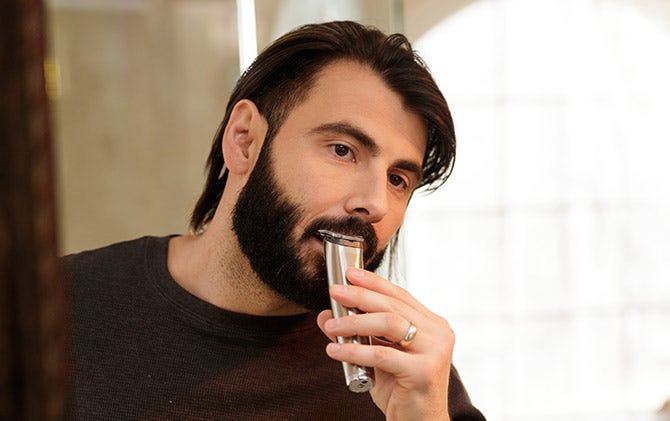 A man cleaning up and shaping his mustache with a Wahl trimmer. 