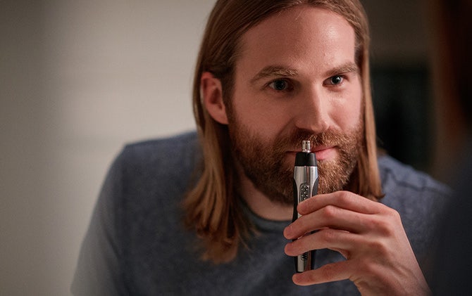 A man cleaning up his mustache with the Wahl ear, nose and brow trimmer.