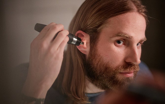 A man cleaning up his ear hair with the Wahl ear, nose and brow trimmer.