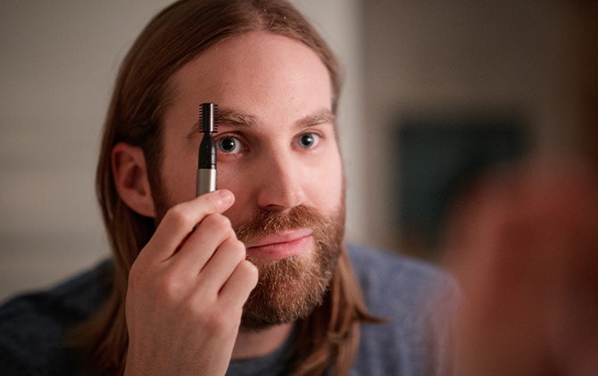 A man cleaning up his eyebrows with the Wahl ear, nose and brow trimmer.