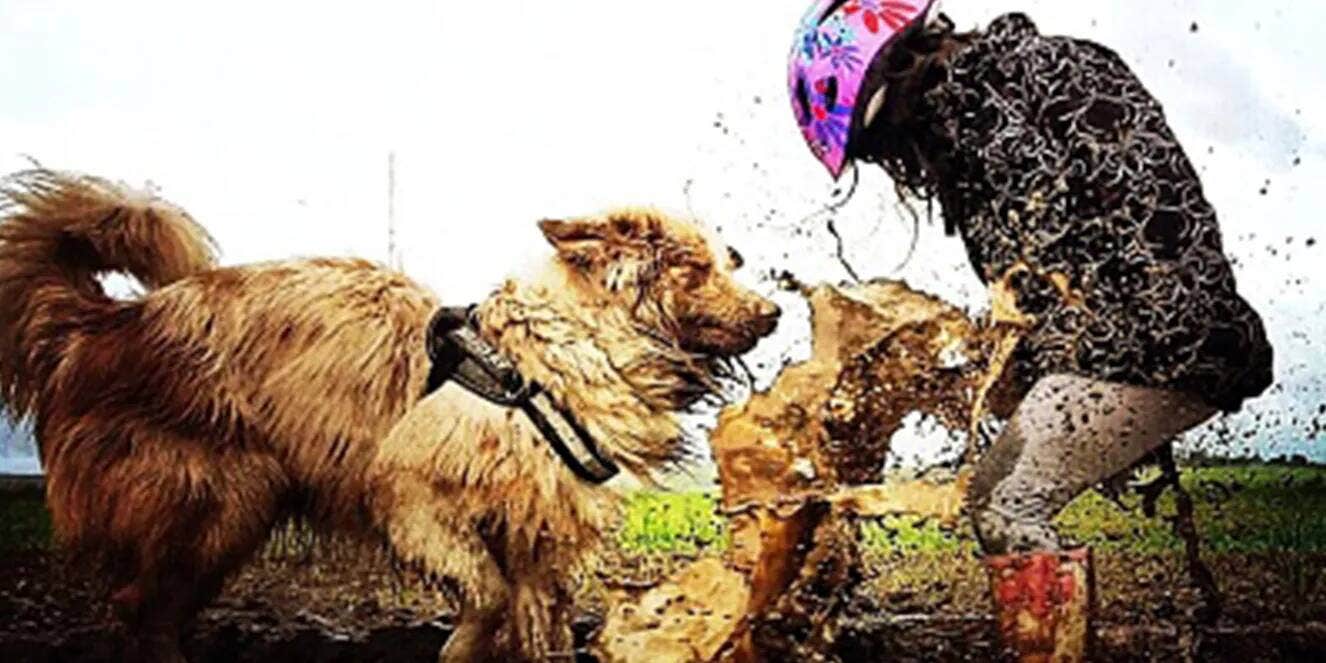 Woman dog walking in mud.