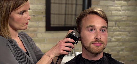 A man getting the arch around his ears touched up after a haircut.