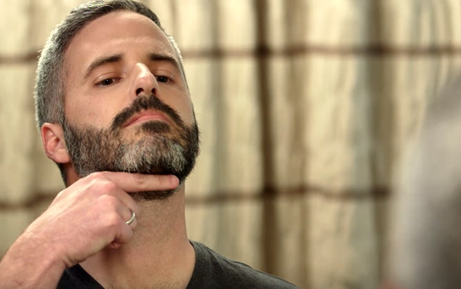 A man identifying where his natural beard line should start.