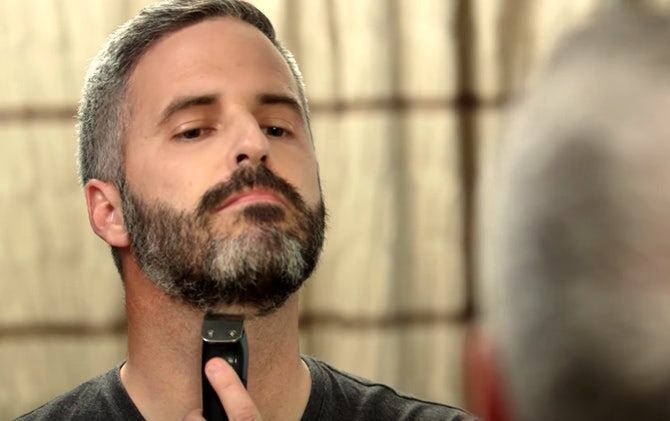 A man trimming up his beard line to shape his beard with a Wahl trimmer. 