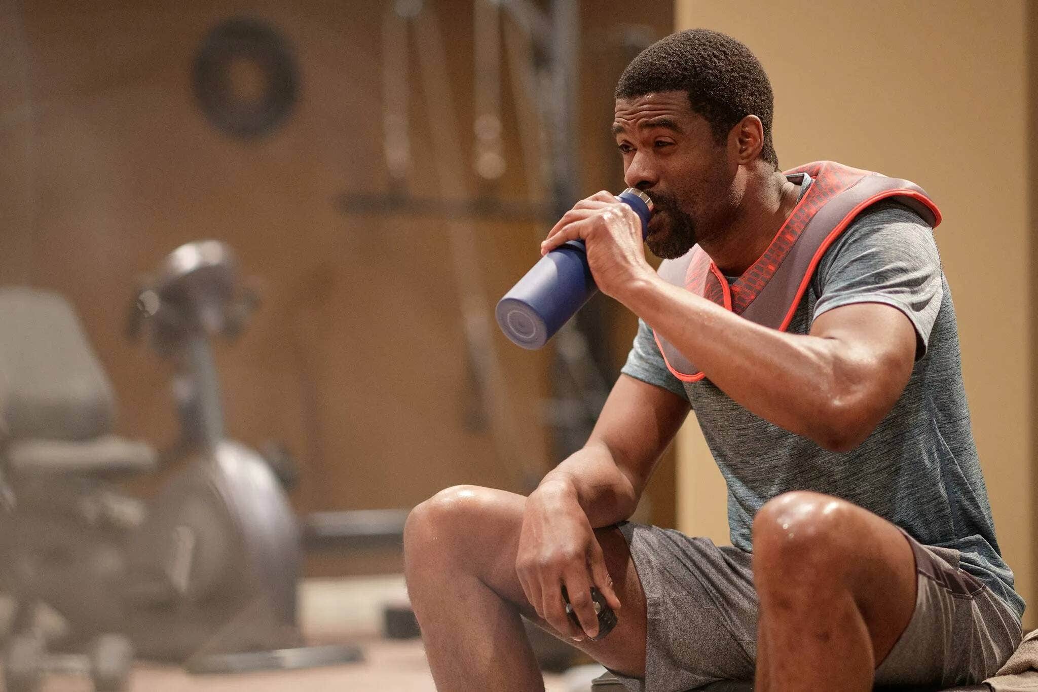 A man drinking water to keep hydrated during a workout. 