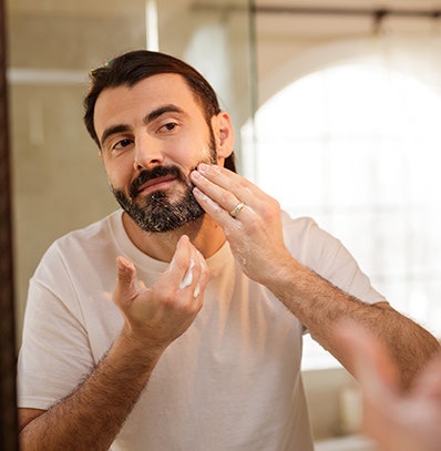 A man washing his beard with Wahl beard & hair care products.