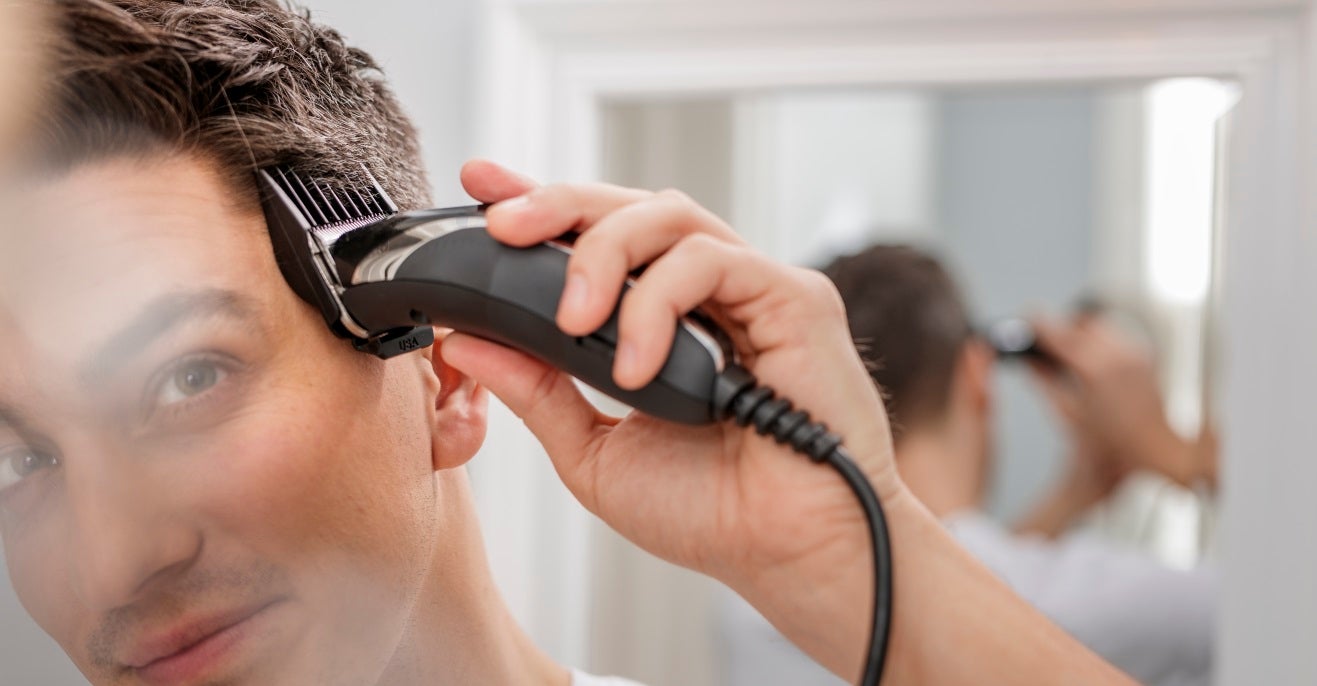 A man using a Wahl hair clipper with a guide comb attachment.