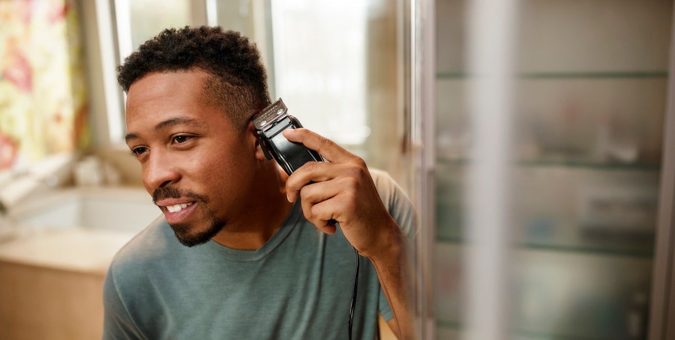 A man using a Wahl hair clipper on the sides of his head. 