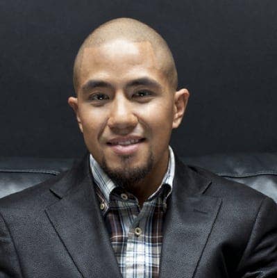 A man smiling with a very short haircut called the close cut.