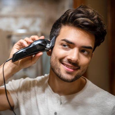 A man giving himself a textured haircut with Wahl hair clippers. 