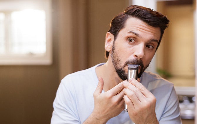 A man shaping his mustache with a Wahl trimmer. 